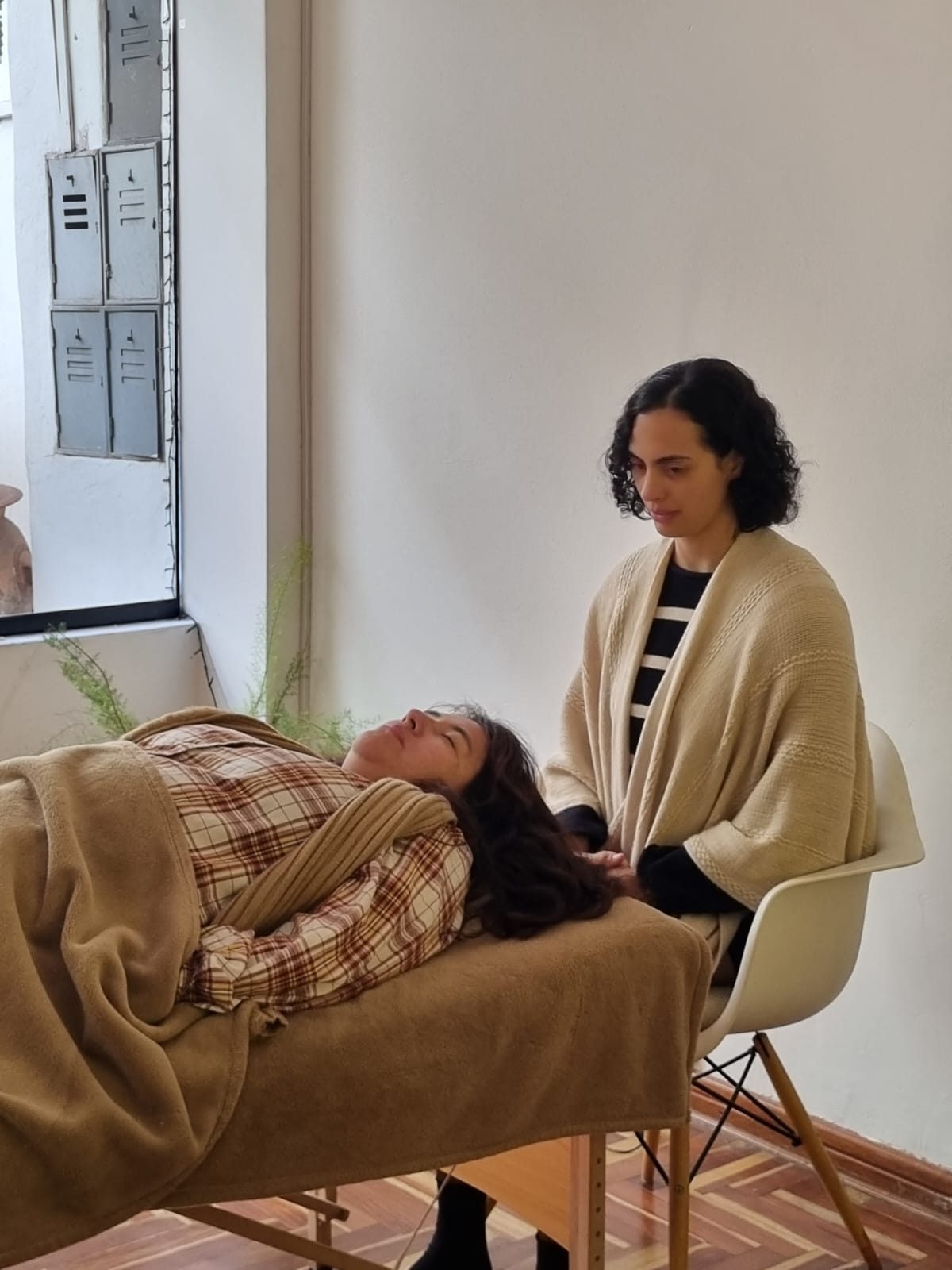 Mafi sentada junto a una camilla acompañando a una consultante que descansa con los ojos cerrados